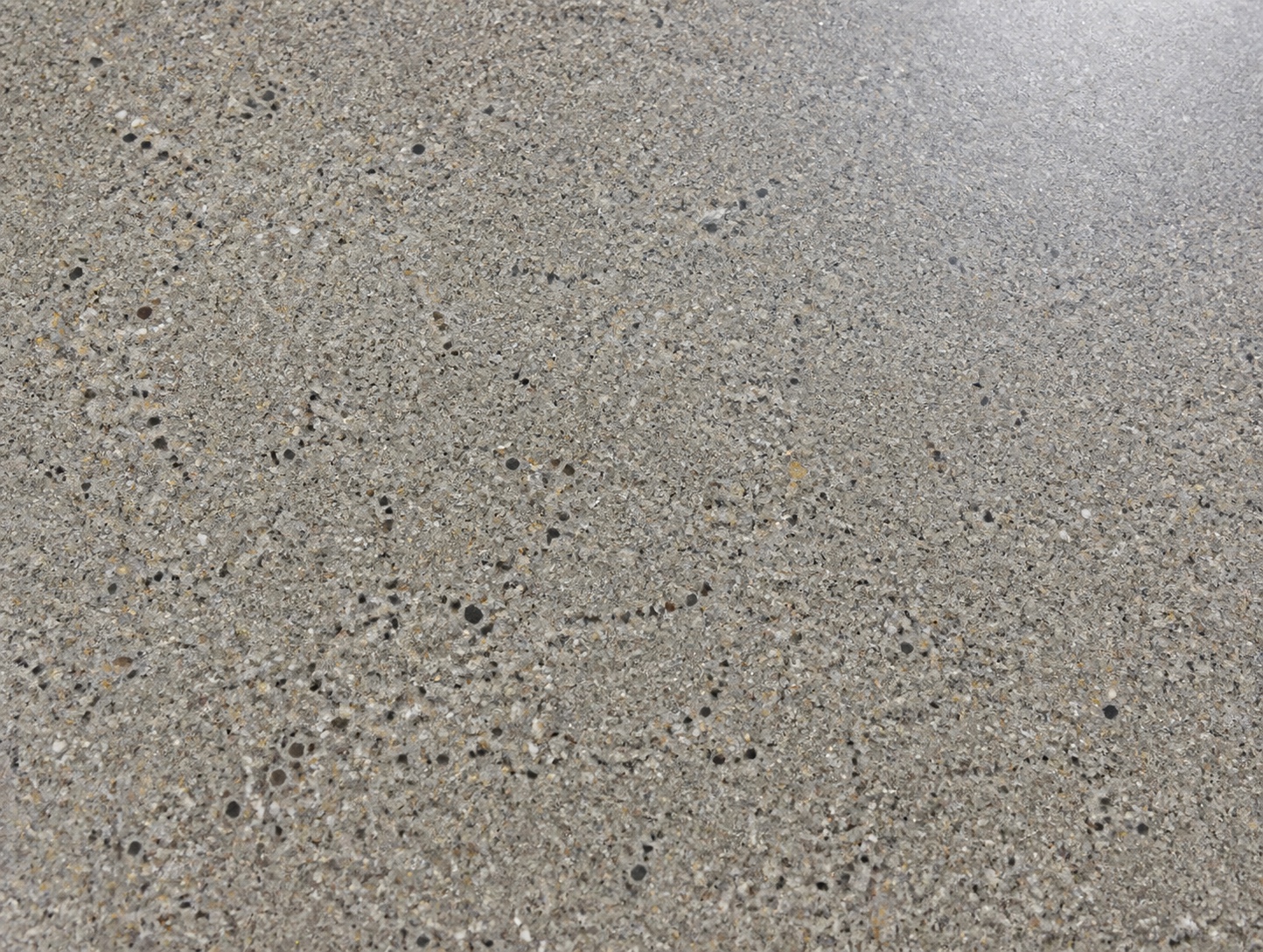 Realistic close-up of Class B salt-and-pepper polished concrete with fine aggregate exposure, shown in the selected satin appearance direction