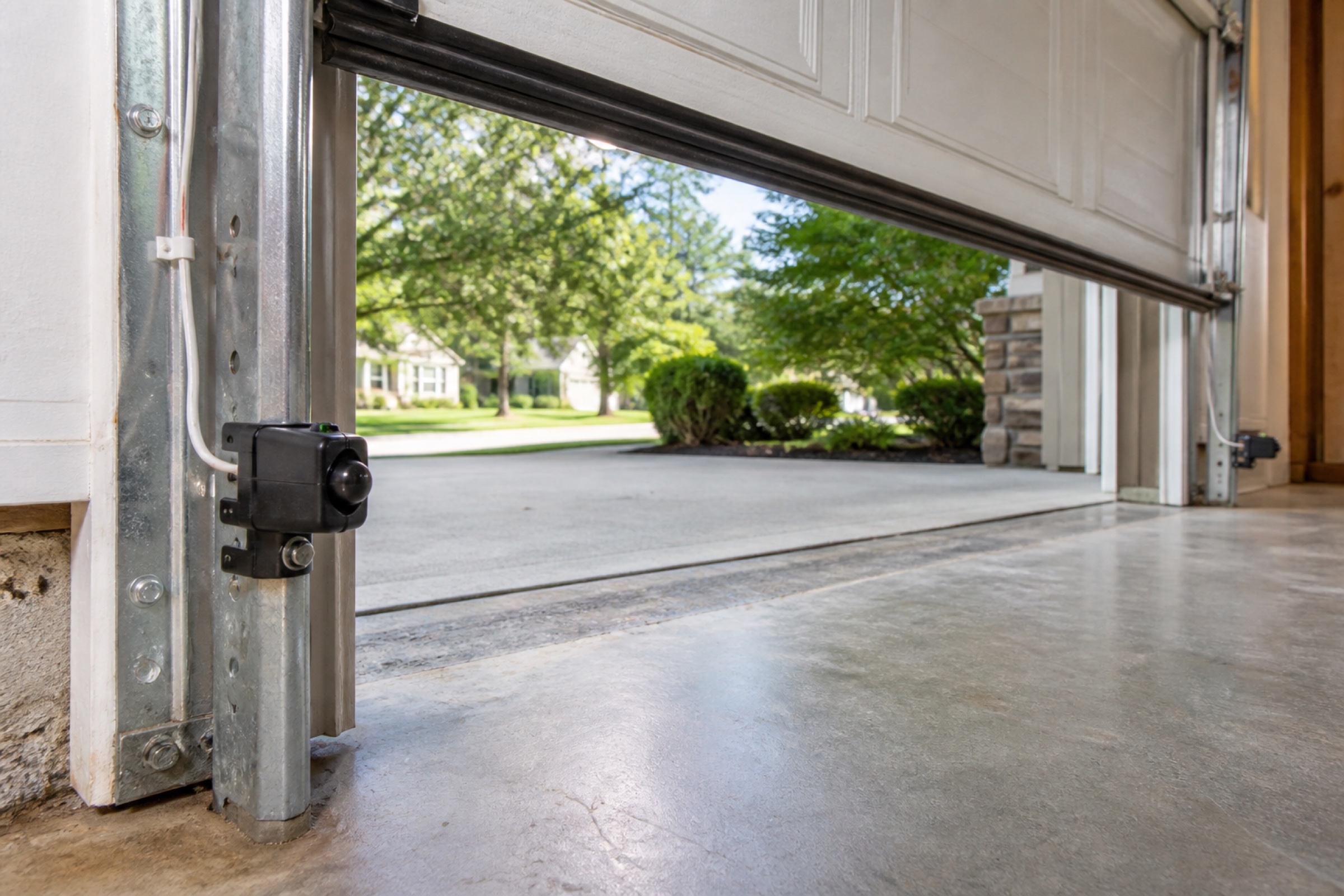 Matched garage door photo-eye safety sensors mounted low on opposite tracks inside a garage